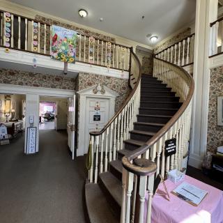 A historic interior featuring a grand curved staircase with decorative banisters and elegant decor.