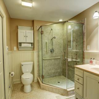 A modern bathroom with a glass-enclosed shower, toilet, and vanity.