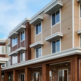 A modern apartment building with multiple stories and large windows.