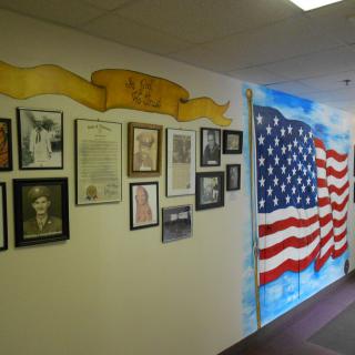 A wall display featuring historical portraits and an American flag mural in a museum setting.