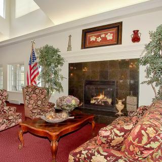 A cozy living room interior with a fireplace, patterned sofas, a coffee table, and an American flag.