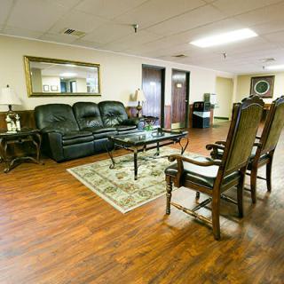 A cozy living room featuring a leather sofa, elegant chairs, and a coffee table on a hardwood floor.