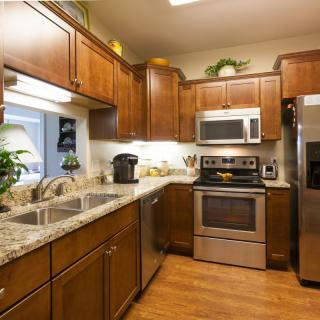 A modern kitchen with wooden cabinets, stainless steel appliances, and granite countertops.