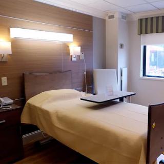 A modern hospital patient room featuring a bed and essential amenities.