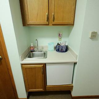 A compact kitchenette with a sink, cabinets, and countertop.