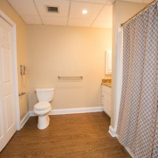 A modern and spacious bathroom featuring a toilet, shower with curtain, and vanity area.