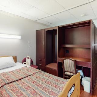 A well-furnished hospital room featuring a bed and storage space.