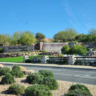 A serene park featuring a waterfall and lush greenery against a clear blue sky.