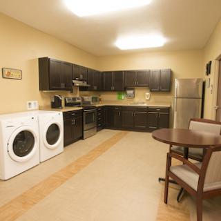 A modern kitchen featuring a laundry area with washing and drying machines, complemented by sleek cabinetry and a dining space.