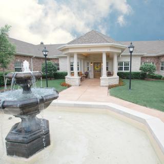 A scenic view of a building with a fountain and landscaped surroundings.