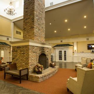A cozy lobby with a central brick fireplace and comfortable seating.