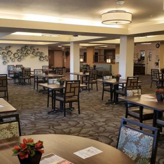 A spacious dining area with neatly arranged tables and chairs, featuring modern lighting and decorative elements on the walls.