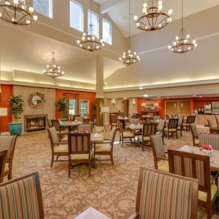 A spacious dining area with elegant chandeliers and neatly arranged tables and chairs.