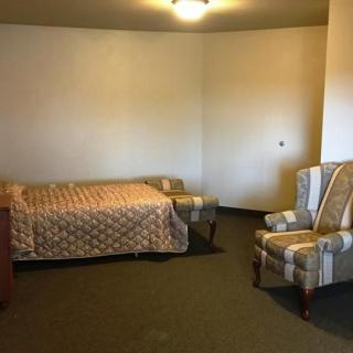 A simple bedroom with a bed and an armchair.