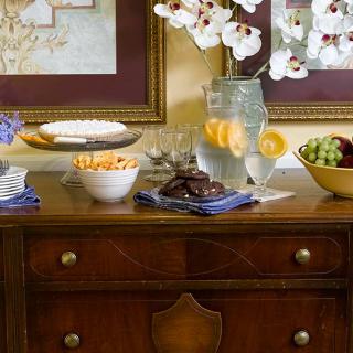 A beautifully arranged table with snacks, fruits, cookies, and a pitcher of lemonade.