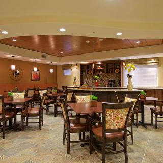 A modern restaurant dining area with tables, chairs, and a bar.