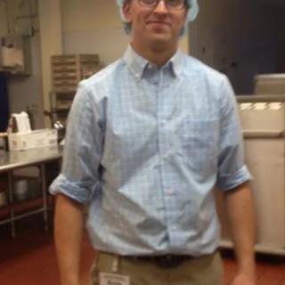 A person wearing a hairnet and glasses in a kitchen setting.