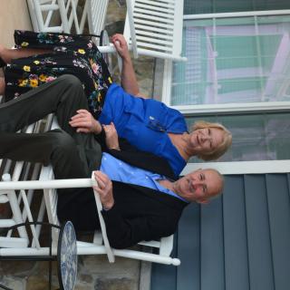 A couple sitting together on rocking chairs on a porch.