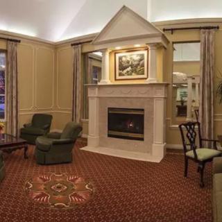 A cozy living room with a central fireplace, surrounded by comfortable armchairs and a patterned carpet.