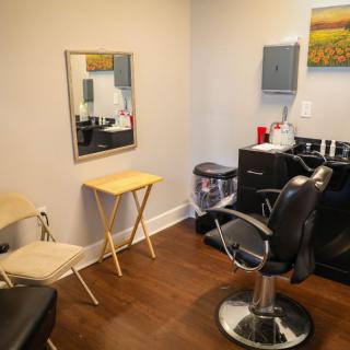 A tidy and organized hair salon with a barber chair, mirror, and necessary equipment.