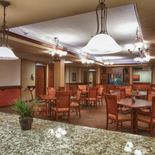 A well-lit dining area with multiple tables and chairs, featuring elegant decor and lighting.