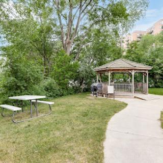 A peaceful park featuring a gazebo surrounded by lush greenery and picnic tables.