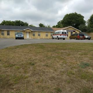 A view of a residential building with an ambulance parked in the driveway on a cloudy day.