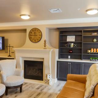 A cozy living room featuring a fireplace, comfortable seating, and a wall-mounted clock.