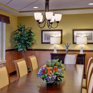 A well-decorated dining room with a wooden table, cushioned chairs, and elegant lighting.
