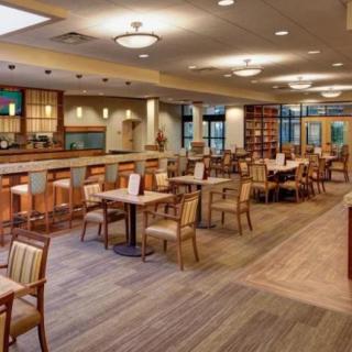 A spacious and well-lit restaurant interior with tables, chairs, and a bar area.