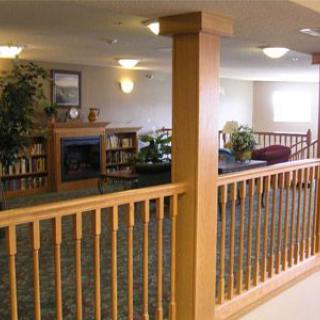 A cozy living room area with a fireplace, wooden railing, and comfortable furniture.