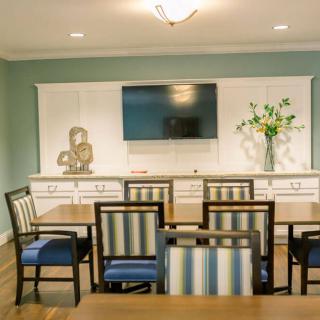 A modern dining room with striped chairs, a mounted television, and decorative elements.