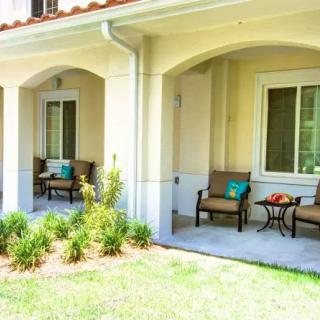 A cozy patio area with comfortable chairs and a small table, surrounded by greenery.