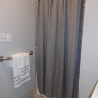 A bathroom with a gray shower curtain and a towel hanging on a bar.