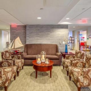 A cozy lobby with a sofa, patterned chairs, and a central coffee table surrounded by nautical decor.