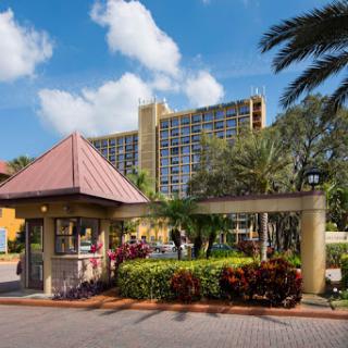 An inviting entrance to a resort, surrounded by lush greenery and palm trees under a clear blue sky.