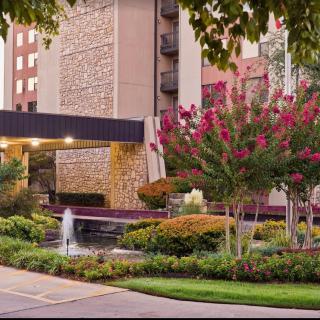 A beautifully landscaped hotel entrance featuring a small fountain and vibrant flowers.