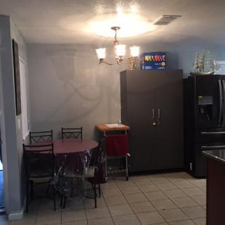 A cozy kitchen and dining area featuring a table with chairs, a refrigerator, and overhead lighting.