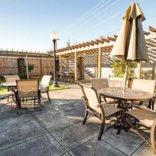 A sunny outdoor patio with seating, tables, and umbrellas.