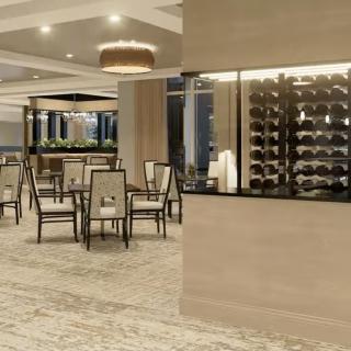 A modern restaurant interior featuring a dining area with stylish tables and chairs, complemented by a wine display.
