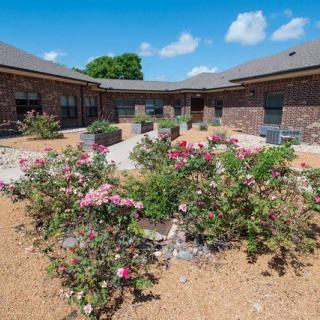 A beautifully landscaped courtyard with vibrant flowers and a brick building backdrop.