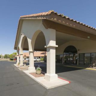 An outdoor view of a hotel entrance with arches and a tiled roof.