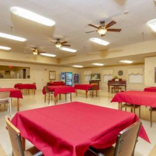 A spacious dining area with red tablecloths and ceiling fans.