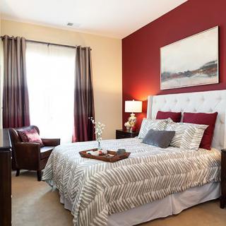 A cozy bedroom with a red accent wall, plush bedding, and stylish decor.