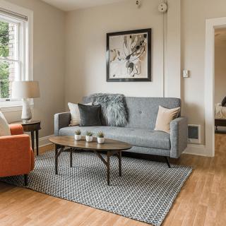 A cozy living room with a gray sofa, an orange armchair, and a modern coffee table.