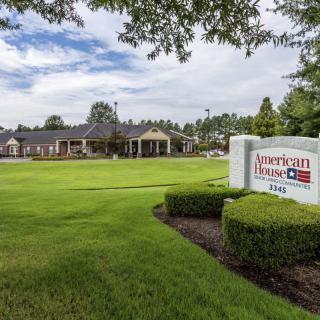 A landscaped area with a building and a prominent sign under a cloudy sky.