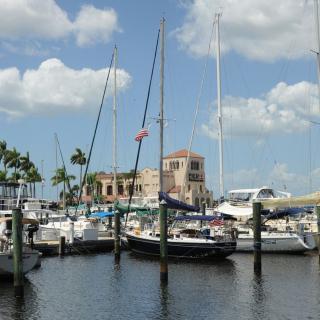 A scenic view of a marina with boats docked under a partly cloudy sky.