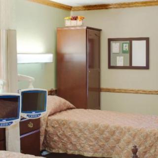 Interior of a hospital room with two beds and wooden furniture.