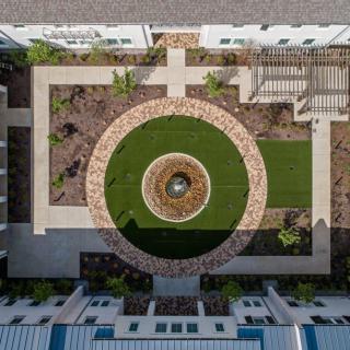 Aerial view of a landscaped courtyard featuring a central fountain and geometric pathways.