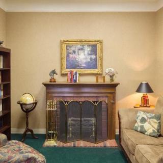 A cozy living room with a fireplace, bookshelf, and traditional decor.